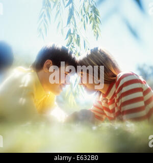 1970s TEENAGE BOY AND GIRL COUPLE LYING IN THE GRASS HEAD TO HEAD ROMANTIC SOFT FOCUS POSE Stock Photo