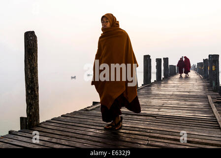 Monks walking on a teak bridge, U Bein Bridge, across Thaungthaman lake, in the morning, Amarapura, Mandalay Division, Myanmar Stock Photo