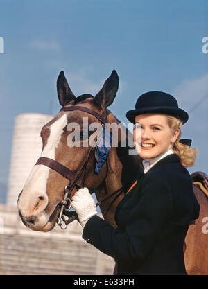 1940s 1950s SMILING WOMAN WEARING EQUESTRIAN RIDING OUTFIT WITH HORSE BLUE RIBBON WINNER FIRST PLACE Stock Photo