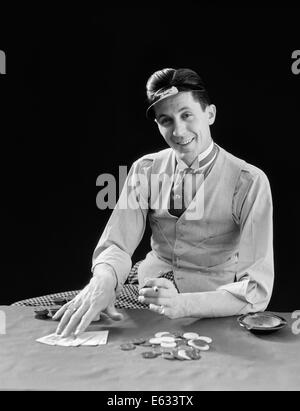 1910s 1920s CHARACTER MAN GAMBLER CARD SHARP SHARK SMILING WEARING VISOR SHOWS HIS CARDS AND BETS POKER CHIPS Stock Photo