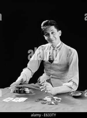 1910s 1920s CHARACTER MAN GAMBLER CARD SHARP SHARK SMILING WEARING VISOR SHOWS HIS CARDS AND BETS POKER CHIPS Stock Photo