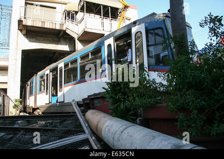 Pasay City, Manila, Philippines. 13th August, 2014. A security guard of the Metro Rail transit system guards the entrance of the main coach of the 3 coach train that slammed on the stop barrier at the Pasay Rotonda station. A three coach train failed to stop at its final station overshooting the barrier and causing injury to its passengers. According to initial reports, about 50 incurred injuries but there was no reported fatalities. Credit:  J Gerard Seguia/Pacific Press/Alamy Live News Stock Photo