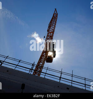 towering crane silhouetted against blazing sun Stock Photo