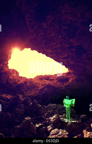 Explorer alien in dramatic cave landscape reading electronic map on future technology flexible display tablet Stock Photo