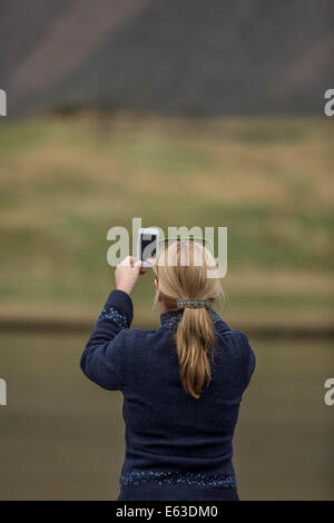 Woman taking a picture of the landscape with a smartphone, Hvalsnes in the Loni valley, Iceland Stock Photo