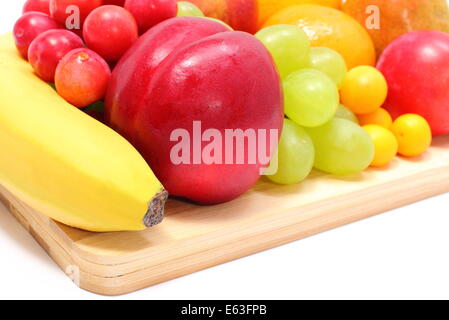 Fresh ripe fruits lying on wooden cutting board, desk of fruits, concept for healthy eating. Isolated on white background Stock Photo