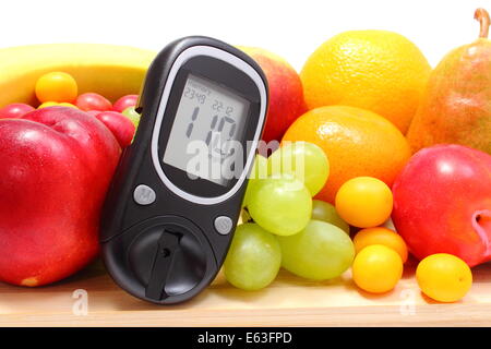 Glucose meter and fresh ripe fruits lying on wooden cutting board, concept for healthy eating and diabetes. Isolated on white ba Stock Photo