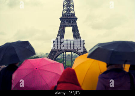 Colorful umbrellas brighten up rainy day view of the Eiffel Tower in Paris France Stock Photo