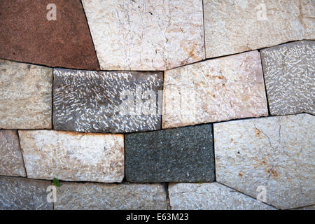 Stone wall with add shaped blocks and various colors and textures of stones Stock Photo