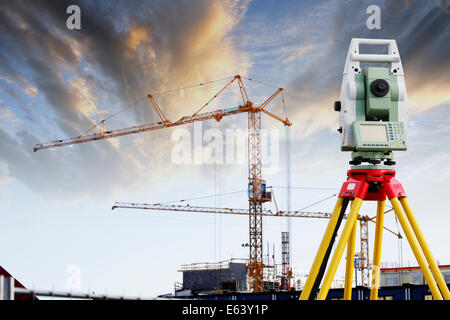 surveying measuring instrument aimed at large building and construction cranes and site Stock Photo