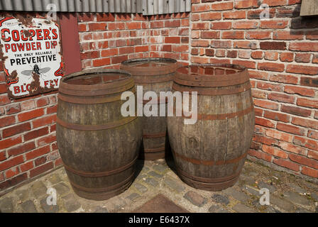 Three wooden beer barrel stored in yard against brick wall. Stock Photo