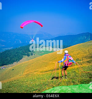 Paraglider preparing for take-off and one in flight at top of Mont Chery Les Gets Savoy French Alps France Stock Photo