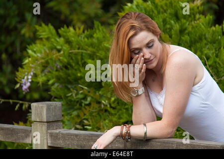 A red haired young girl crying by a bridge Stock Photo