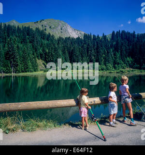 Children angling at Les Mines d'Or lake Morzine resort Savoy French Alps France Stock Photo