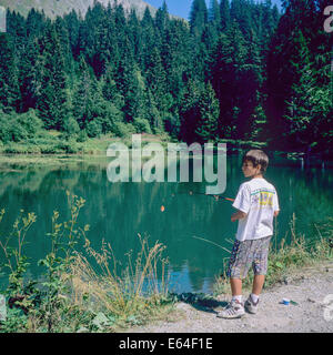 Boy angling at Les Mines d'Or lake Morzine resort Savoy French Alps France Stock Photo