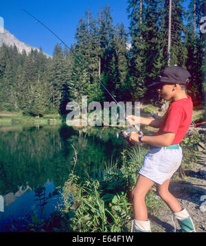 Boy angling at Les Mines d'Or lake Morzine resort Savoy French Alps France Stock Photo