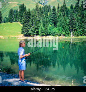 Boy angling at Les Mines d'Or lake Morzine resort Savoy French Alps France Europe Stock Photo