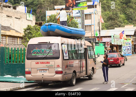 BANOS, ECUADOR - FEBRUARY 25, 2014: Unidentified person standing on a rubber boat tied to the roof rack of a minibus Stock Photo
