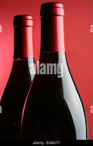Two corked wine bottles closeup over red background Stock Photo
