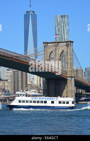 New York ferry passing under the Brooklyn Bridge as it cruises along the East River.