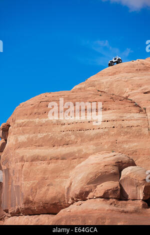 4WD vehicle installed on a steep slope of a large red rock. Utah, USA. Stock Photo