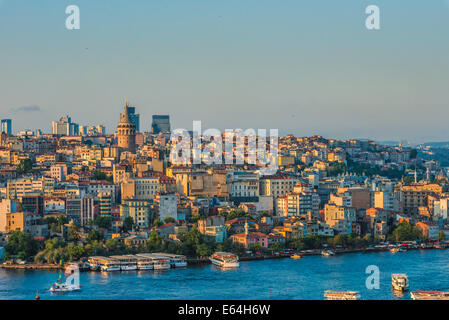 Ferries pass along the Bosphorus with Galata Tower in the distance around sunset. Stock Photo