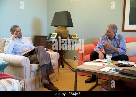 US President Barack Obama talks with Attorney General Eric Holder about the race riots over the killing of a young unarmed black student in a suburb of St. Louis from his vacation August 14, 2014 in Chilmark, Massachusetts. Stock Photo