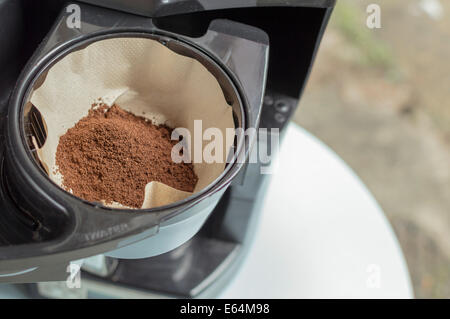 Filter paper fitted into a filter coffee machine cup, raw coffee grounds placed into the dry paper waiting to be used. Stock Photo