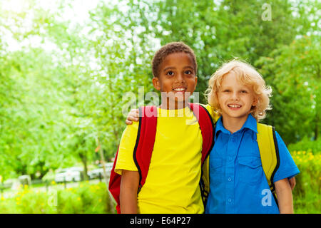 Two happy boys wearing school bags stand together Stock Photo