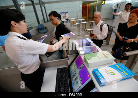 Beijing, China. 14th Aug, 2014. A quarantine staff member hands out brochures about preventing Ebola virus disease to passengers arriving at Beijing Capital International Airport in Beijing, capital of China, Aug. 14, 2014. To prevent the deadly Ebola virus from entering China, China's quarantine authority implements stricter inspections on inbound flights from regions affected by Ebola and step up sanitary measures on incoming goods. Credit:  Shen Bohan/Xinhua/Alamy Live News Stock Photo