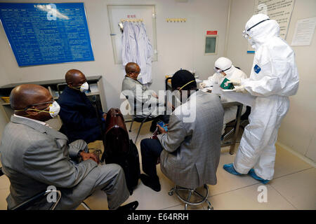 Beijing, China. 14th Aug, 2014. Quarantine staff members fill up questionary for four passengers who came from Ebola-infected Nigeria at the Beijing Capital International Airport in Beijing, capital of China, Aug. 14, 2014. To prevent the deadly Ebola virus from entering China, China's quarantine authority implements stricter inspections on inbound flights from regions affected by Ebola and step up sanitary measures on incoming goods. Credit:  Shen Bohan/Xinhua/Alamy Live News Stock Photo