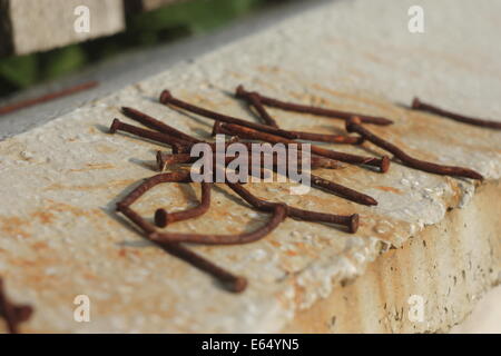 Rusted nails placed on a dappled concrete wall Stock Photo