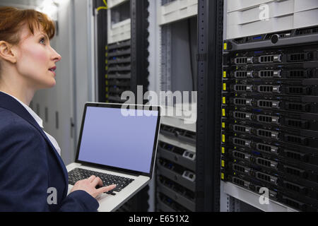 Pretty technician using laptop while working on servers Stock Photo