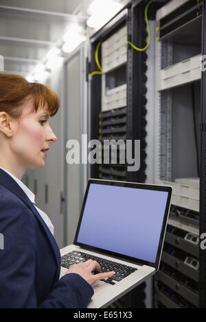 Pretty technician using laptop while working on servers Stock Photo
