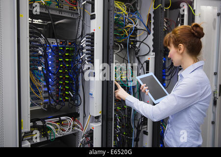 Technician using tablet pc while analysing server Stock Photo