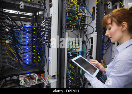 Technician using tablet pc while analysing server Stock Photo