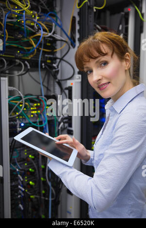 Smiling technician using tablet pc while analysing server Stock Photo