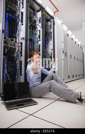 Stressed technician sitting on floor beside open server Stock Photo