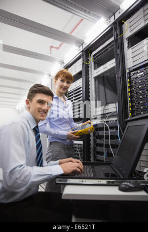 Team of technicians using digital cable analyser on servers Stock Photo