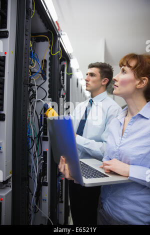 Team of technicians using digital cable analyser on servers Stock Photo