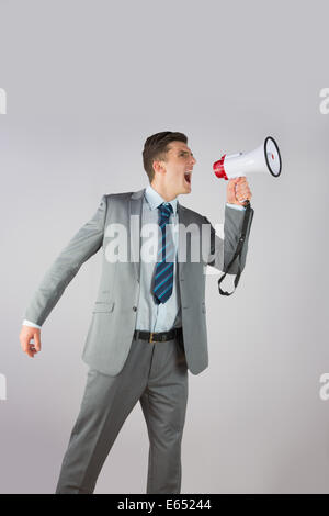 Angry businessman shouting through megaphone Stock Photo