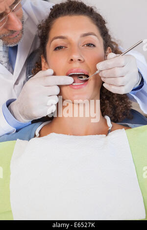 Dentist examining a patients teeth in the dentists chair Stock Photo
