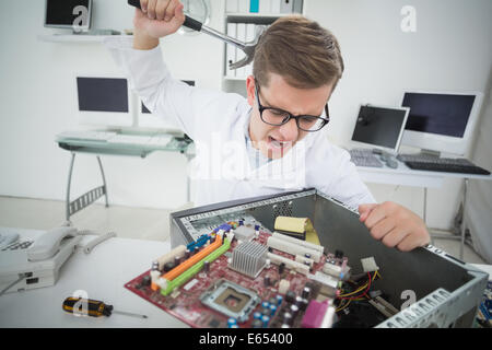 Computer engineer holding hammer over broken console Stock Photo