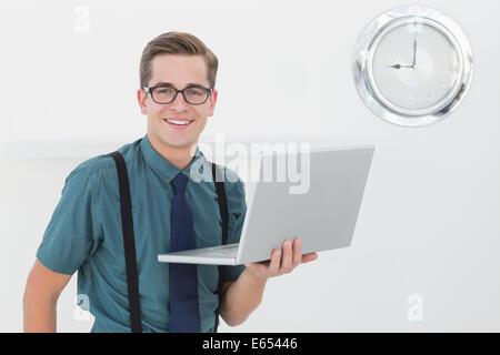 Nerdy businessman holding laptop smiling at camera Stock Photo