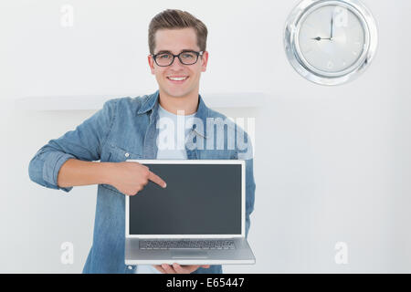 Nerdy businessman holding laptop smiling at camera Stock Photo