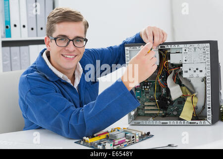 Smiling technician working on broken computer Stock Photo