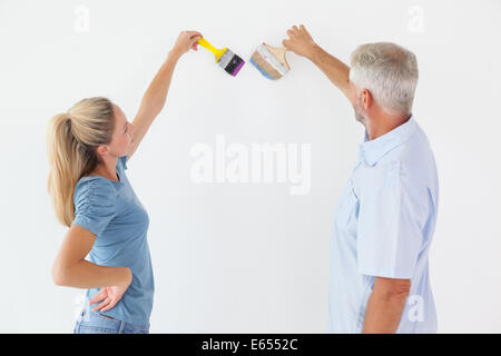 Happy couple painting wall with paintbrushes Stock Photo
