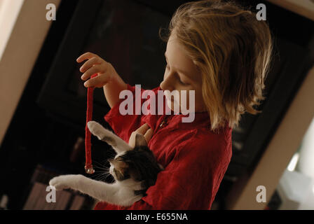 Children playing - Young girl playing with her pet cat in the living room Stock Photo