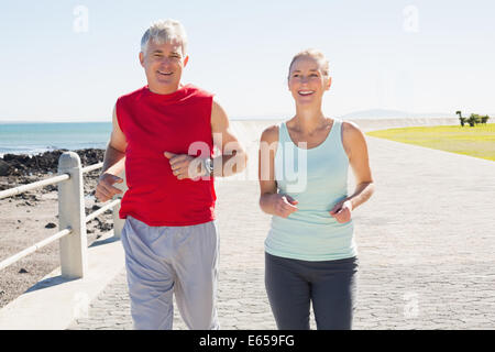 Fit mature couple jogging on the pier Stock Photo