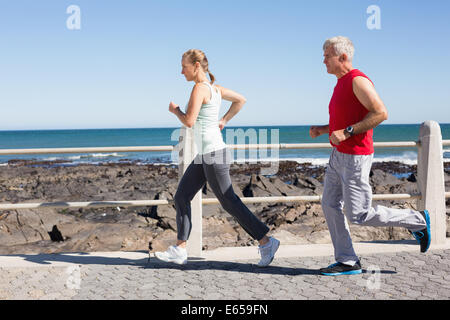Fit mature couple jogging together on the pier Stock Photo